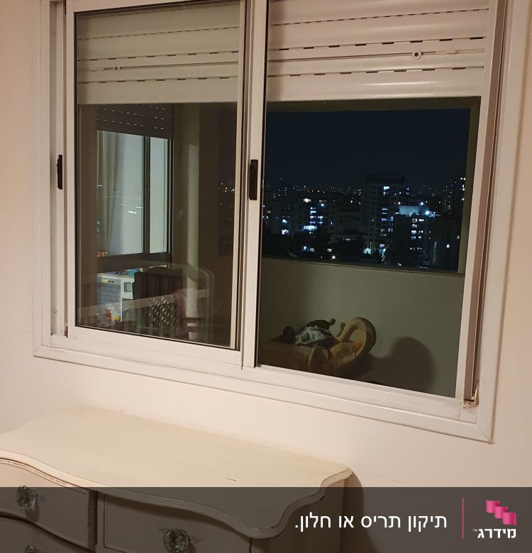 תריסים לבנים סגורים בחלון זכוכית כפול